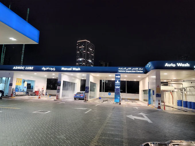 UAE car service center with vehicle inspection and auto wash facilities at night.